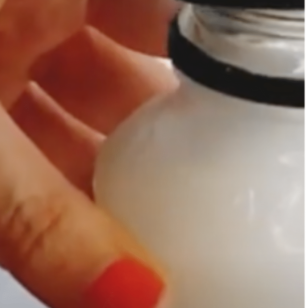 una mano sujeta una botella que contiene el friega suelos casero