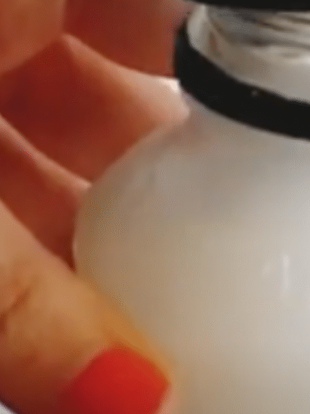 una mano sujeta una botella que contiene el friega suelos casero