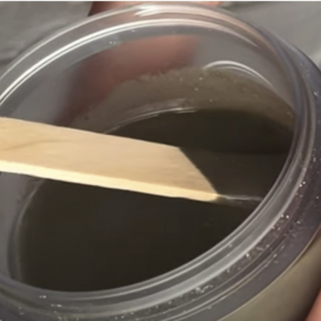 pasta de dientes casera en un tarro de cristal. Se esta cogiendo un poco con espátula de madera