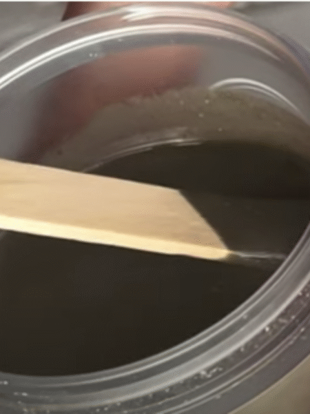 pasta de dientes casera en un tarro de cristal. Se esta cogiendo un poco con espátula de madera