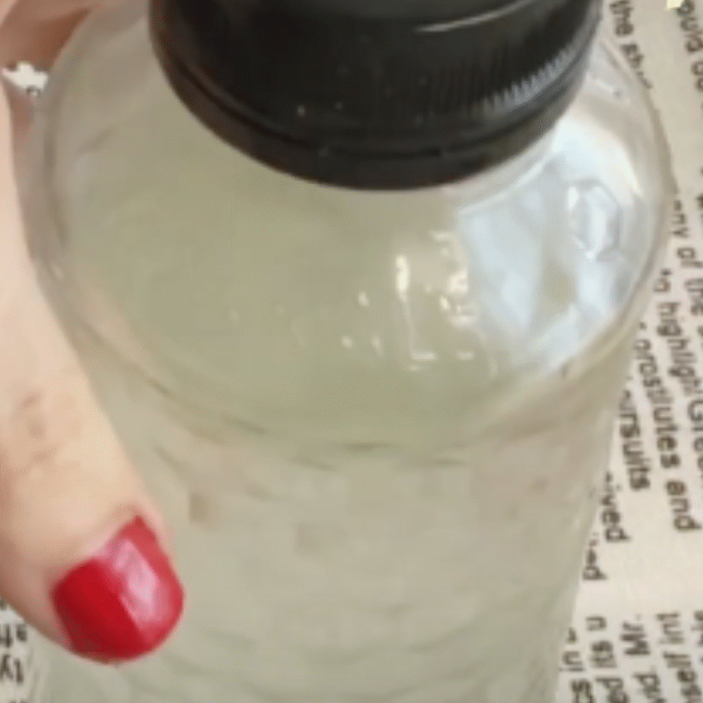 una mano sujeta una botella con el suavizante casero