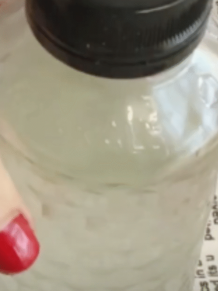 una mano sujeta una botella con el suavizante casero