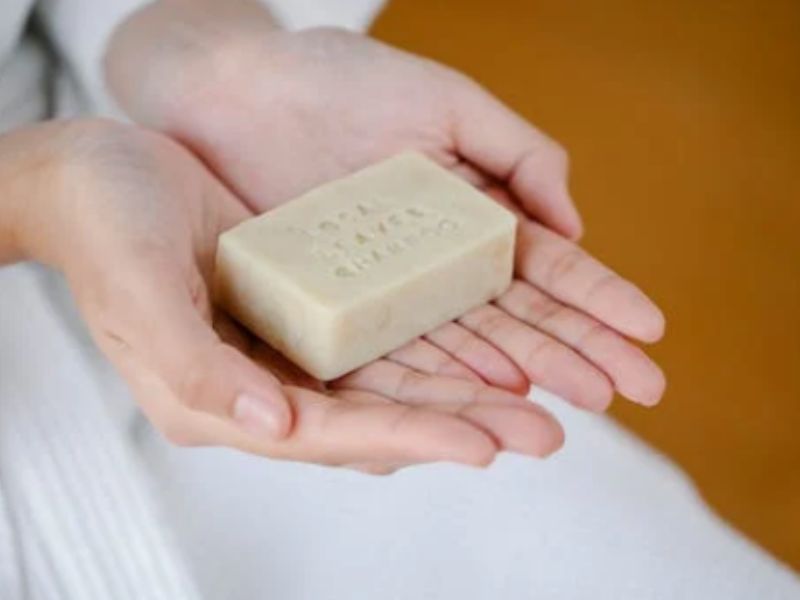 manos muestran el champú para pelo graso